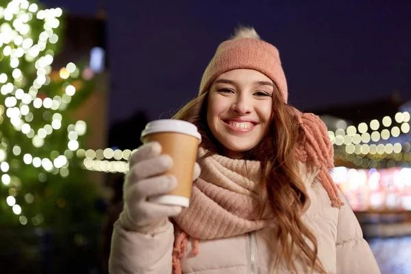 Gelukkig jonge vrouw met koffie op kerstmarkt — Stockfoto