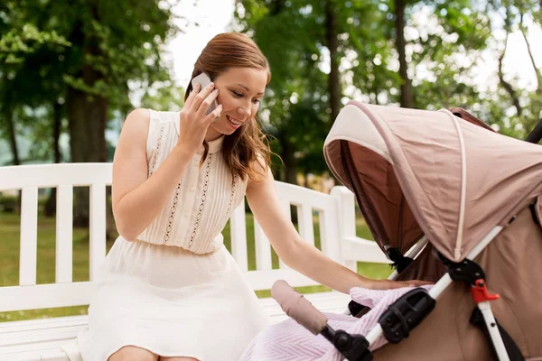 Mutter mit Kinderwagen ruft Smartphone im Park an — Stockfoto