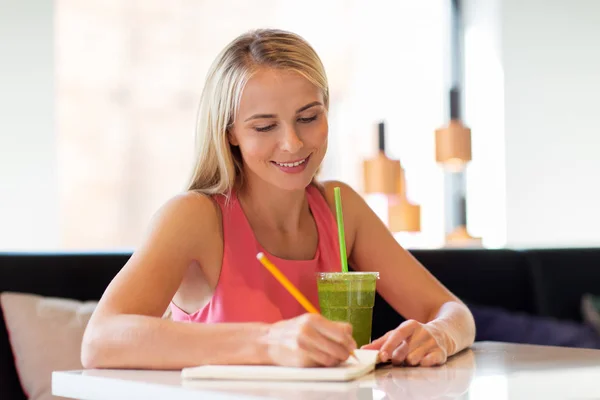 Mulher com bebida escrevendo para notebook no restaurante — Fotografia de Stock