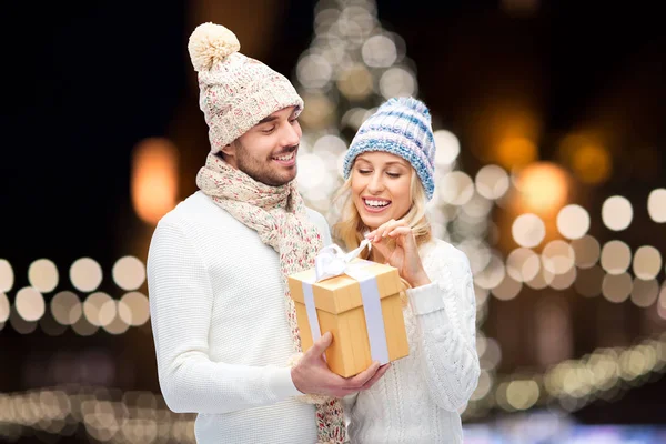 Feliz pareja con regalo de Navidad sobre luces de noche — Foto de Stock