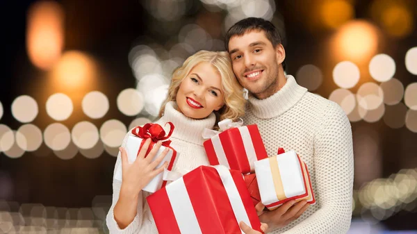 Heureux couple en chandails tenant des cadeaux de Noël — Photo