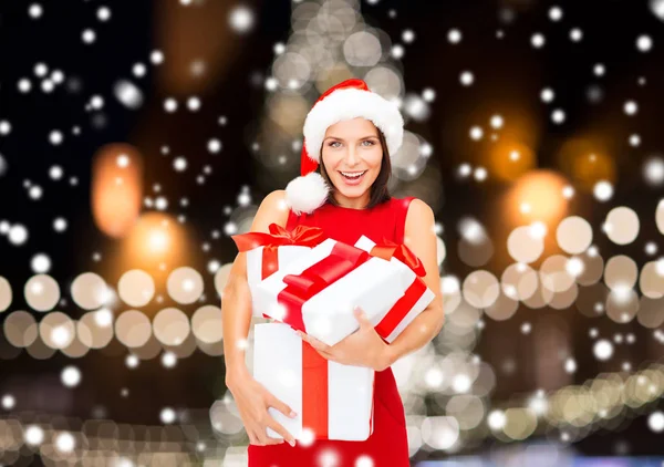 Усміхнена жінка в капелюсі Санта з подарунковими коробками — стокове фото