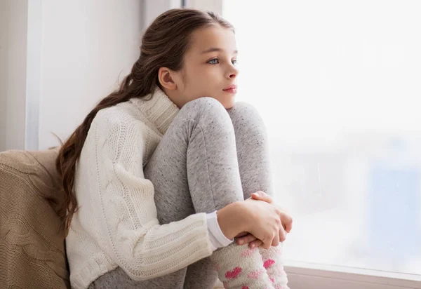 Smutna dziewczyna siedzi na parapet w domu okna w zimie — Zdjęcie stockowe