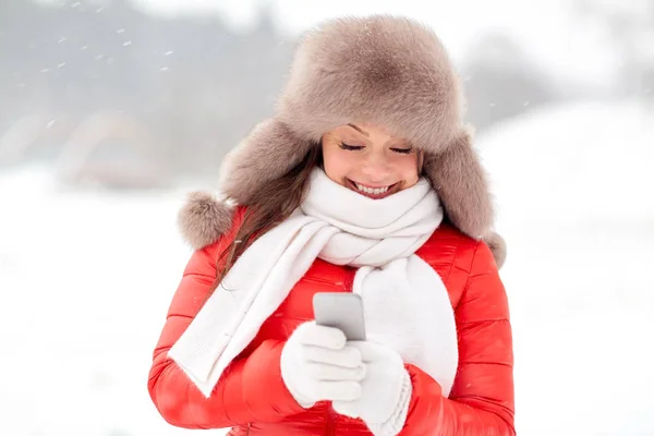 Счастливая женщина в зимней меховой шляпе со смартфоном — стоковое фото