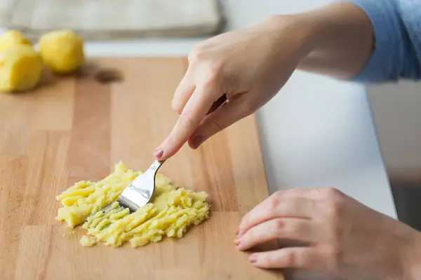 Tangan dengan garpu membuat kentang tumbuk di papan — Stok Foto