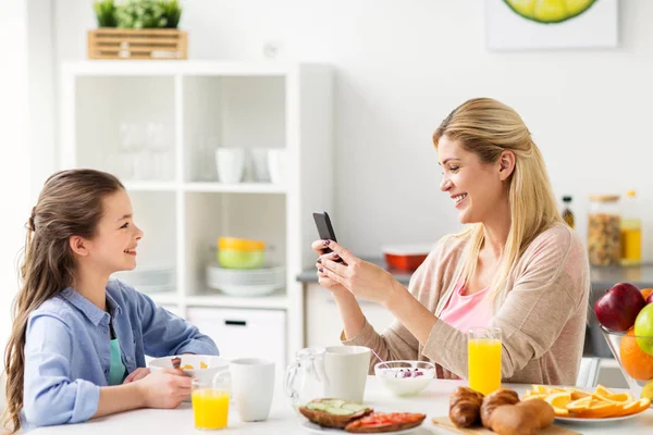 Family with smartphone having breakfast at home — Stock Photo, Image