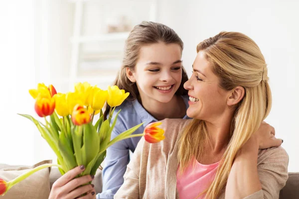 Mutlu kız evde annesine çiçek veriyor. — Stok fotoğraf