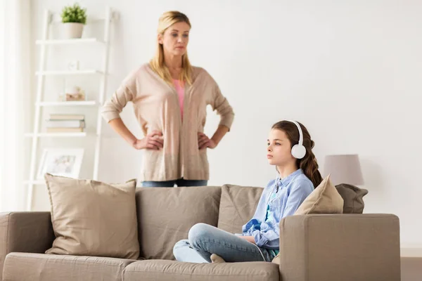 Mädchen mit Kopfhörern und wütender Mutter zu Hause — Stockfoto