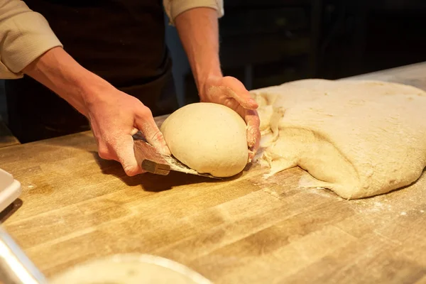 Baker portioning dough with bench cutter at bakery — Stock Photo, Image