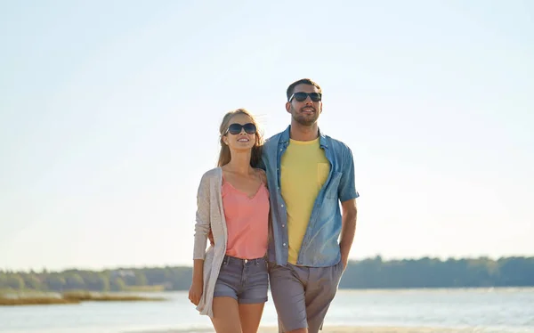 Felice coppia in occhiali da sole che si abbraccia sulla spiaggia estiva — Foto Stock