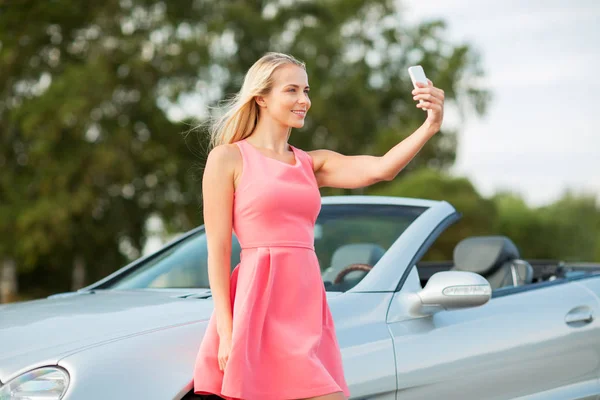 Žena představuje kabrioletem a pořizování selfie — Stock fotografie