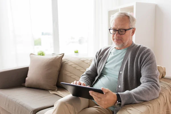 Старший чоловік з планшетним ПК сидить на дивані вдома — стокове фото