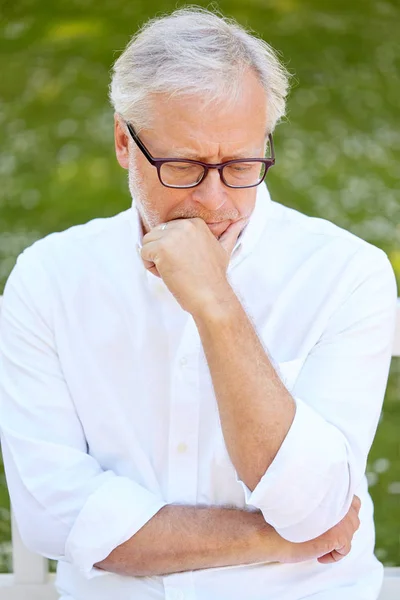 Thoughtful senior man sitting at summer park — Stock Photo, Image