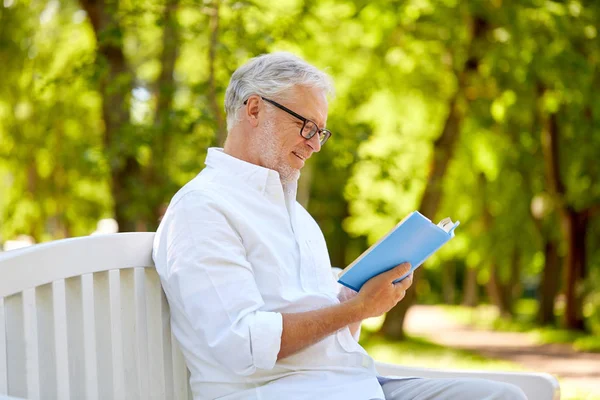 Glücklicher Senior liest Buch im Sommerpark — Stockfoto