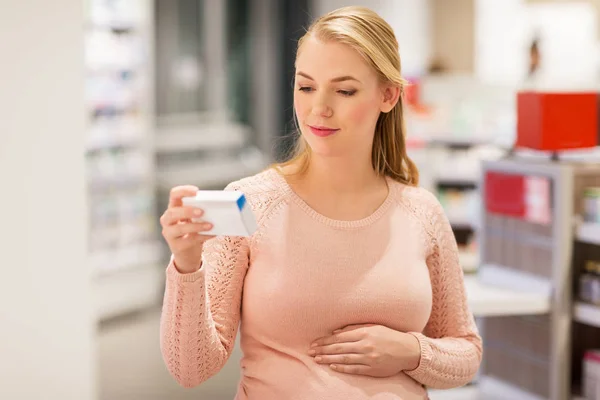 Gelukkig zwangere vrouw met medicatie bij apotheek — Stockfoto