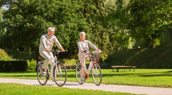 Felice coppia di anziani a cavallo biciclette al parco estivo — Foto Stock