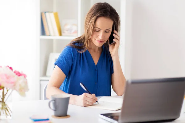 Mujer con bloc de notas llamando en el teléfono inteligente en la oficina — Foto de Stock