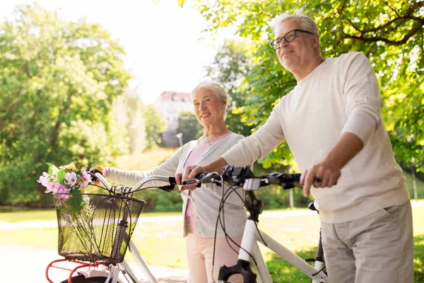 Feliz casal sênior com bicicletas no parque de verão — Fotografia de Stock