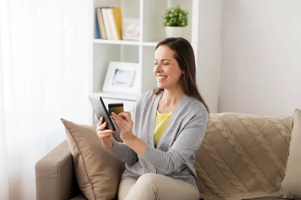 Femme heureuse avec tablette pc et carte bancaire à la maison — Photo