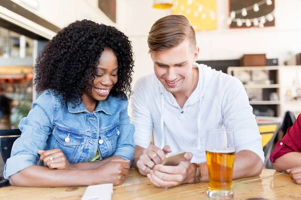 Homme et femme heureux avec smartphone au bar — Photo