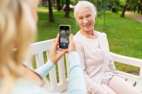 Daughter photographing senior mother by smartphone — Stock Photo, Image
