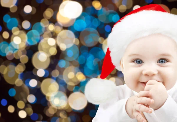 Heureux bébé dans le chapeau de Père Noël sur les lumières de Noël — Photo