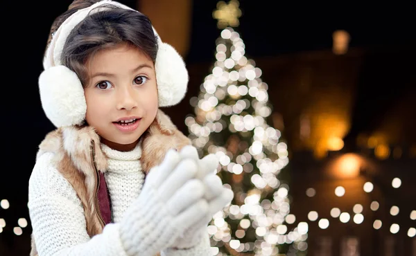 Ευτυχισμένος κορίτσι φορώντας ωτοασπίδες πάνω από τα φώτα των Χριστουγέννων — Φωτογραφία Αρχείου