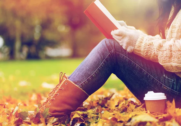 Frau mit Buch trinkt Kaffee im Herbstpark — Stockfoto