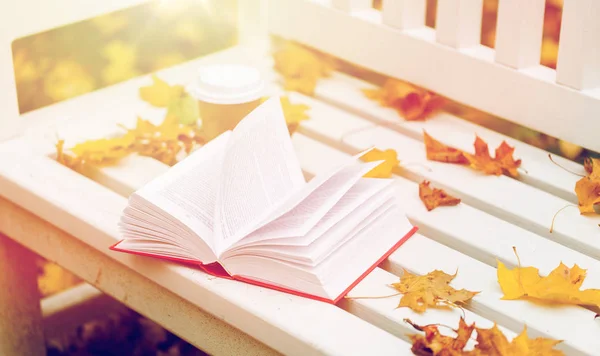 Livre ouvert et tasse de café sur banc dans le parc d'automne — Photo