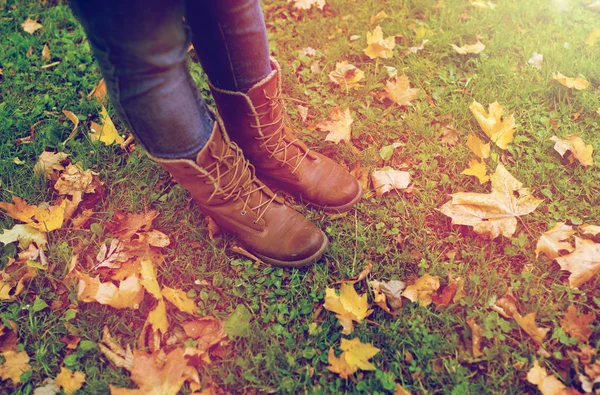 Piedi femminili in stivali e foglie di autunno su erba — Foto Stock