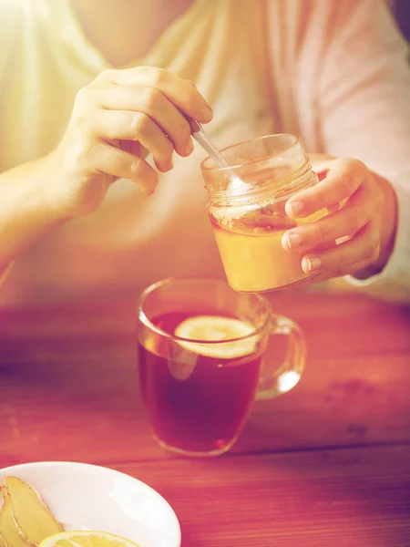 Primer plano de la mujer que añade miel al té con limón — Foto de Stock