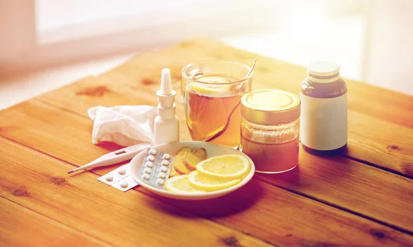 Gyógyszerek, a hőmérő, a méz és a csésze tea-fa Stock Kép
