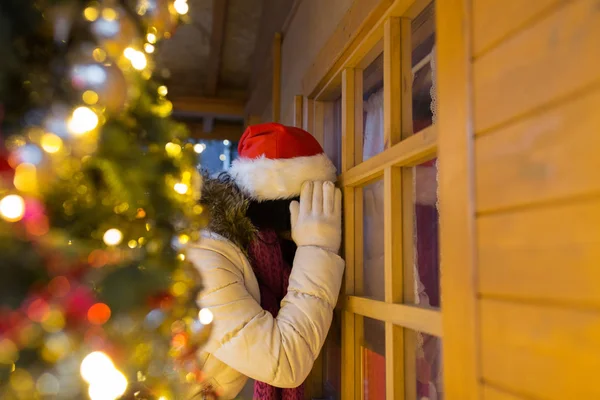 Femme qui cherche à la fenêtre de la maison au marché de Noël — Photo