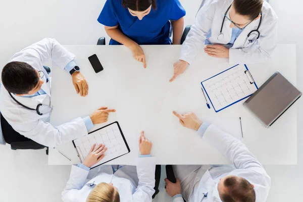 Groupe de médecins avec cardiogrammes travaillant à table — Photo