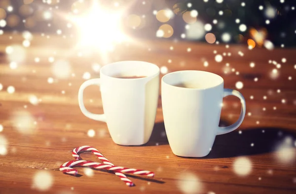 Weihnachtsbonbons und Tassen auf Holztisch — Stockfoto