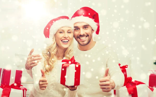 Casal feliz com presentes de Natal e polegares para cima — Fotografia de Stock