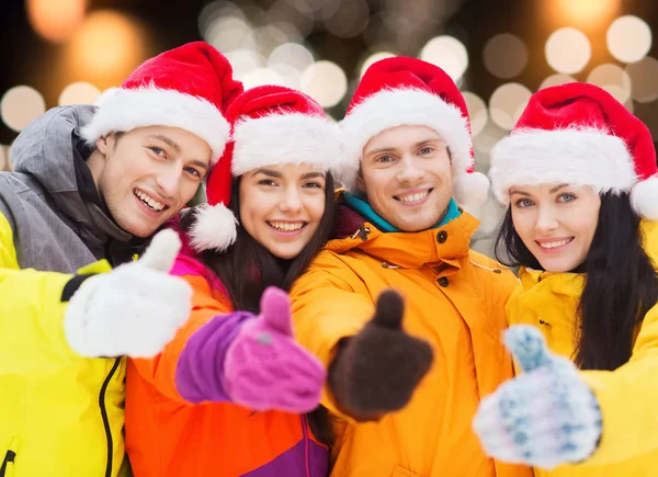 Amigos felices en sombreros de santa y trajes de esquí al aire libre — Foto de Stock