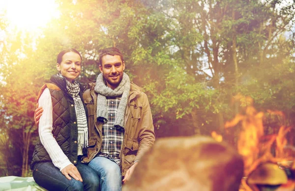 Feliz pareja sentada en el banco cerca del fuego del campamento — Foto de Stock