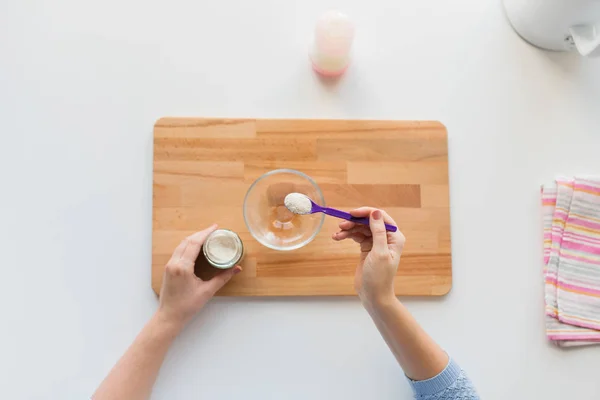 Hände mit Löffel und Glas machen Baby-Müsli — Stockfoto