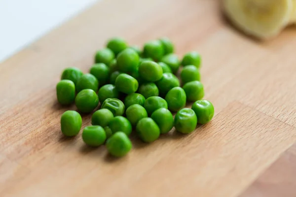 Gros plan de pois verts sur planche à découper en bois — Photo