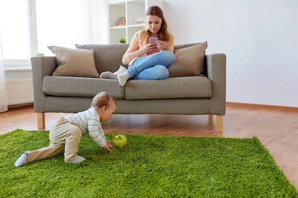 Mère avec smartphone et bébé jouant à la maison — Photo