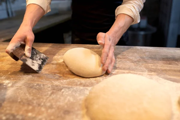 Baker portioning dough with bench cutter at bakery — Stock Photo, Image