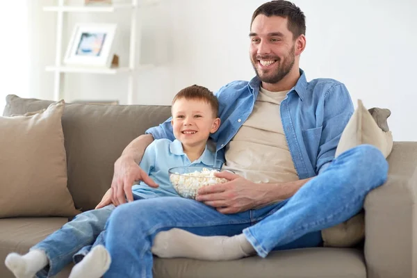Батько і син з попкорном дивитися телевізор вдома Стокова Картинка
