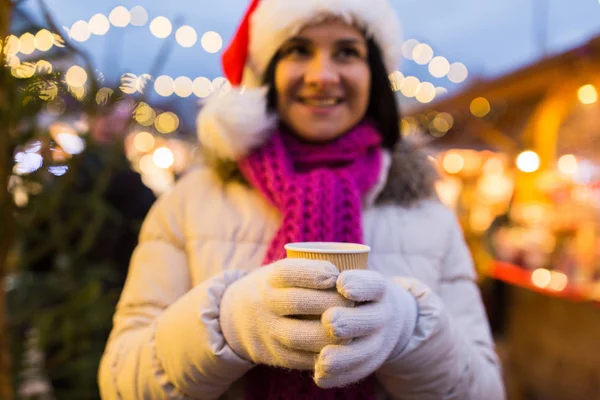 Kobieta z kubkiem gorącego napoju na Jarmark bożonarodzeniowy — Zdjęcie stockowe
