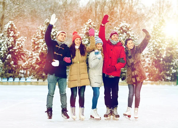 Happy přátelé bruslení na kluzišti venku — Stock fotografie