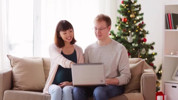 Hombre y esposa embarazada con portátil en Navidad — Vídeos de Stock