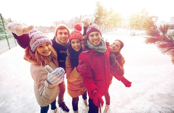 Amigos felices con smartphone en pista de patinaje sobre hielo —  Fotos de Stock