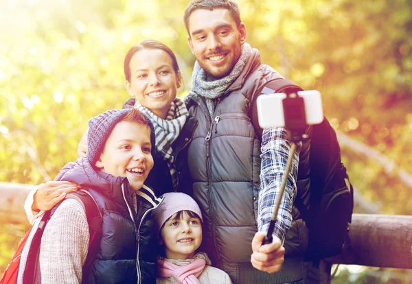 Gelukkige familie met smartphone selfie stok in bos — Stockfoto