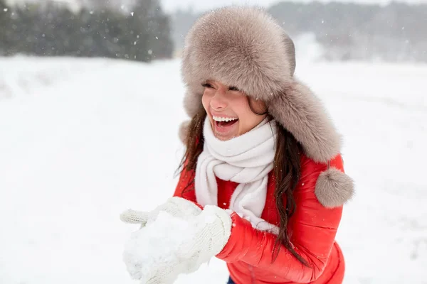 Щаслива жінка зі снігом в зимовому капелюсі на відкритому повітрі — стокове фото