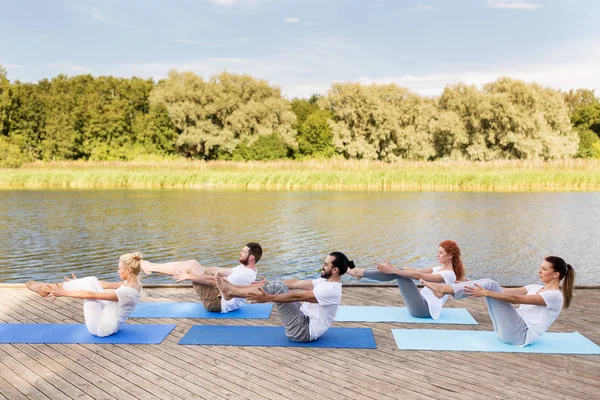 Människor gör yoga i halv-boat pose utomhus — Stockfoto